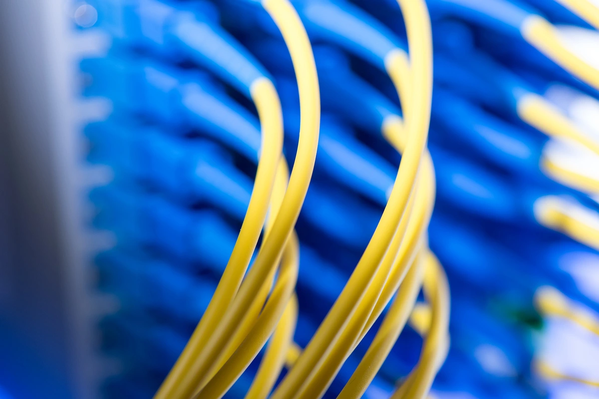 fiber-optic-cable-design-yellow-patch-cords-blue-panel Close-up of yellow fiber jumpers in front of a blue patch panel, illustrating fiber optic cable design for high-speed links.