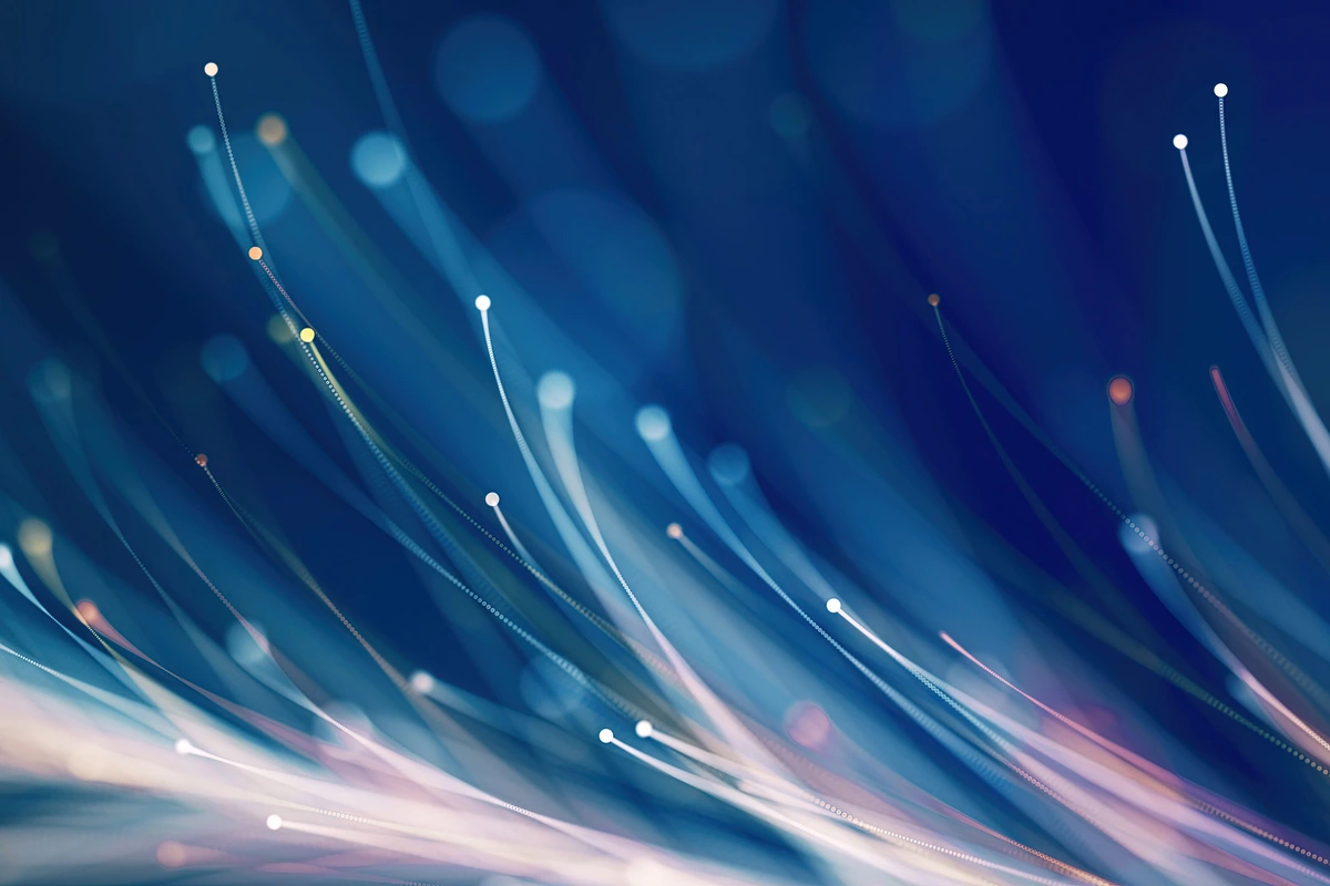 Abstract light trails on deep blue background, symbolizing data moving through fiber optic cables over copper wire.