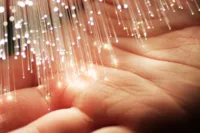 Close-up of a hand under glowing fiber strands—visual for How to Choose the Best Fiber Installer in Prescott.